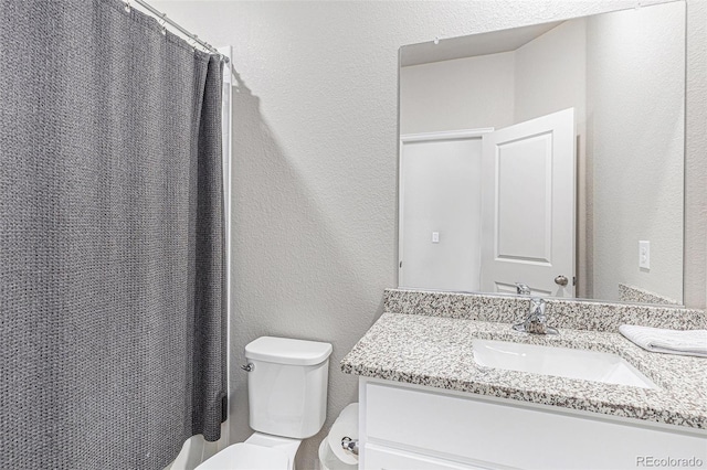 bathroom featuring vanity, curtained shower, and toilet