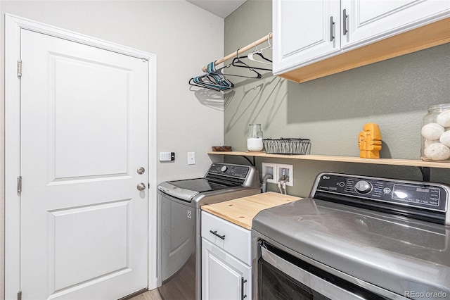 laundry area with cabinets, washing machine and clothes dryer, and wood-type flooring