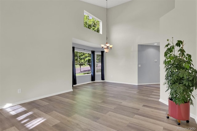 3109 S Jebel Way, Aurora, CO 80013 - unfurnished room with a chandelier, healthy amount of natural light, baseboards, a high ceiling, and wood finished floors