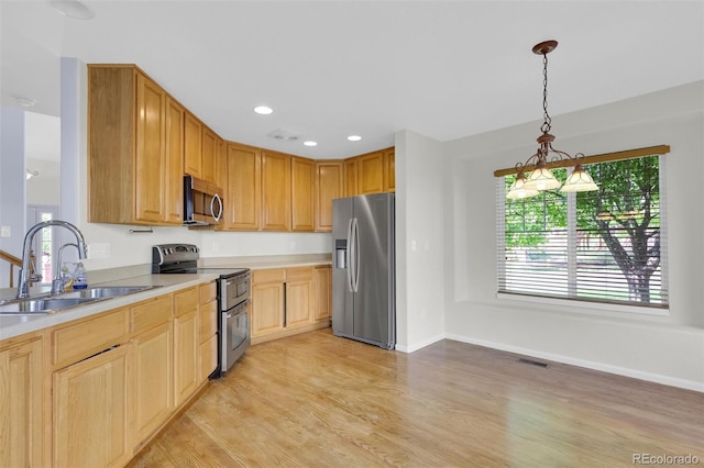 3109 S Jebel Way, Aurora, CO 80013 - kitchen featuring appliances with stainless steel finishes, a sink, light countertops, light wood finished floors, and decorative light fixtures
