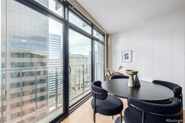 dining room with a wall of windows and hardwood / wood-style floors