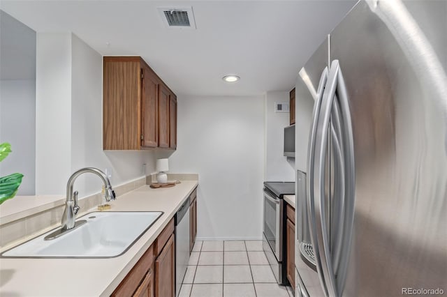 kitchen with appliances with stainless steel finishes, sink, and light tile patterned floors