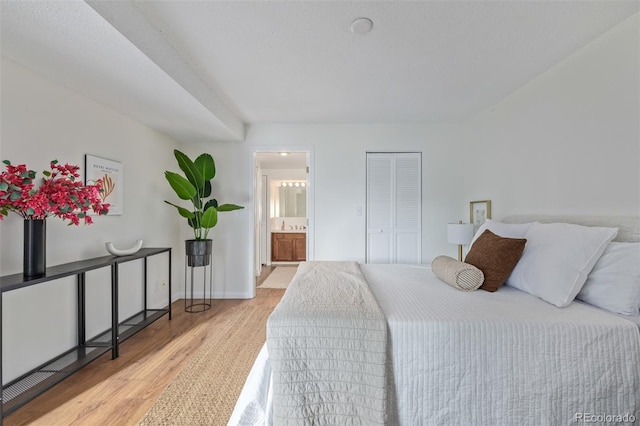 bedroom featuring ensuite bath, a closet, and light wood-type flooring