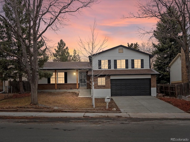 tri-level home with driveway, an attached garage, fence, and brick siding