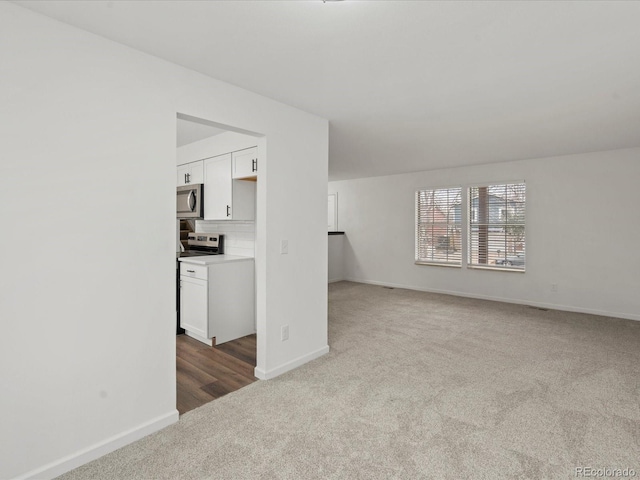 unfurnished living room with carpet floors and baseboards