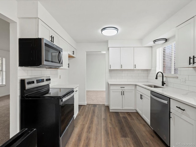 kitchen featuring appliances with stainless steel finishes, white cabinetry, a sink, and decorative backsplash