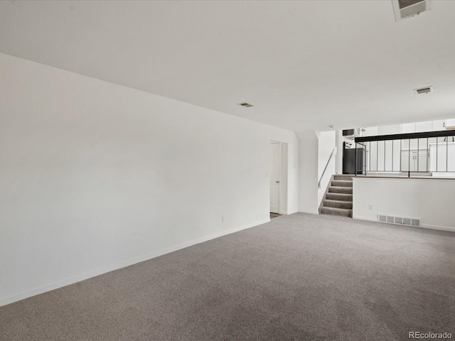 carpeted empty room featuring visible vents, stairway, and baseboards