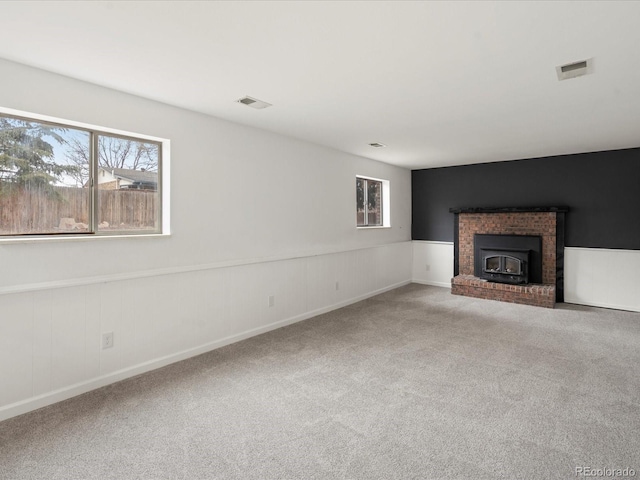 unfurnished living room featuring carpet, a wainscoted wall, and visible vents