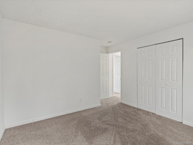 unfurnished bedroom featuring carpet floors, a closet, a textured ceiling, and baseboards