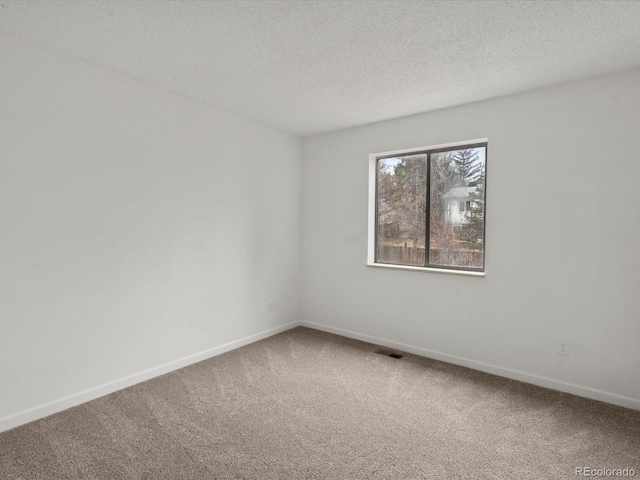 carpeted empty room featuring visible vents, baseboards, and a textured ceiling