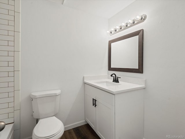 bathroom featuring toilet, wood finished floors, vanity, and baseboards