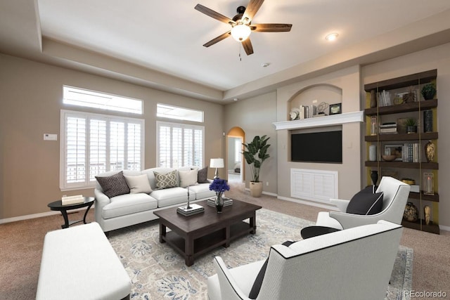 carpeted living room with ceiling fan and a tray ceiling