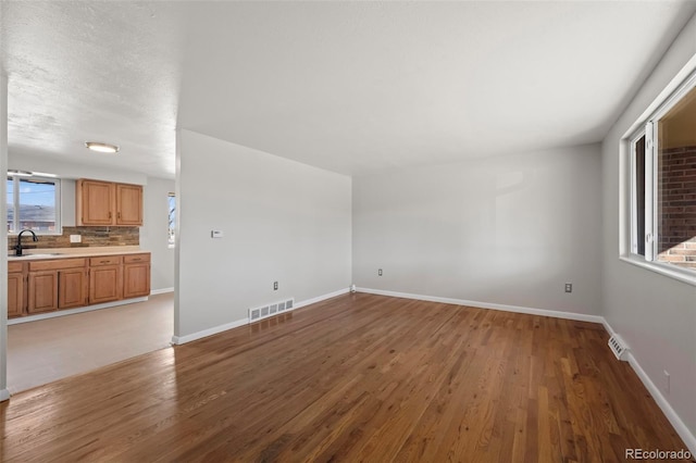 unfurnished living room featuring sink and light hardwood / wood-style flooring