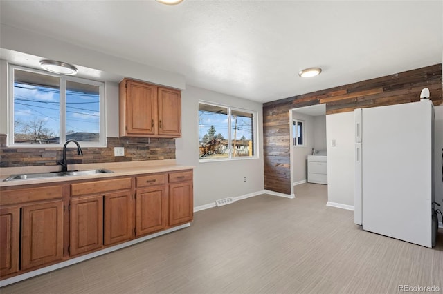 kitchen featuring sink, white refrigerator, washer / clothes dryer, and tasteful backsplash