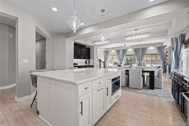 1815 Avery Way, Castle Rock, CO 80109 - kitchen featuring open floor plan, light wood-style flooring, recessed lighting, a raised ceiling, and light stone countertops