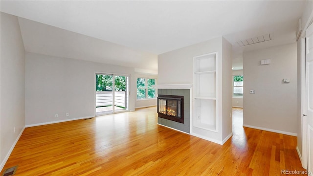 1006 Homestake Dr Unit 1D, Golden, CO 80401 - unfurnished living room with light wood finished floors, plenty of natural light, a tile fireplace, and built in shelves