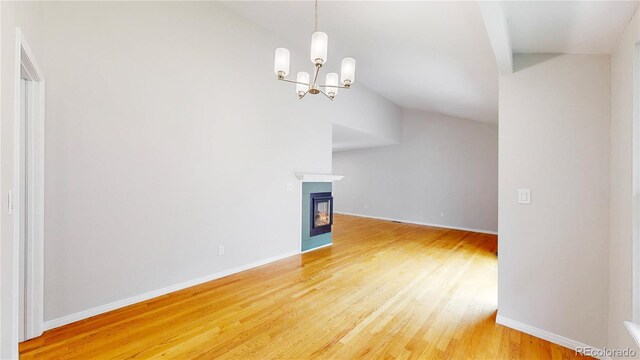 1006 Homestake Dr Unit 1D, Golden, CO 80401 - unfurnished living room with vaulted ceiling, light wood-style flooring, a chandelier, and a glass covered fireplace