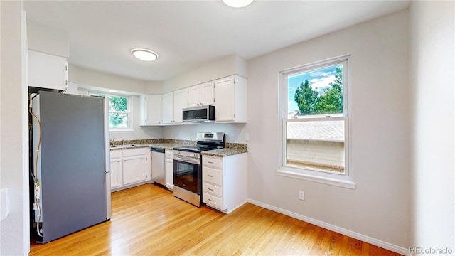 1006 Homestake Dr Unit 1D, Golden, CO 80401 - kitchen featuring appliances with stainless steel finishes, white cabinets, light wood finished floors, and light stone counters