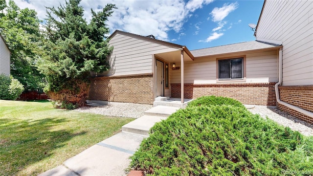 1006 Homestake Dr Unit 1D, Golden, CO 80401 - view of exterior entry with brick siding and a yard