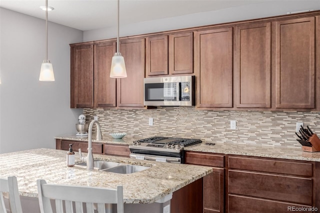 kitchen featuring a breakfast bar, appliances with stainless steel finishes, pendant lighting, and sink