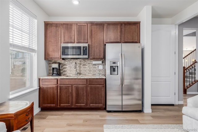 kitchen with light wood-type flooring, stainless steel appliances, and a healthy amount of sunlight