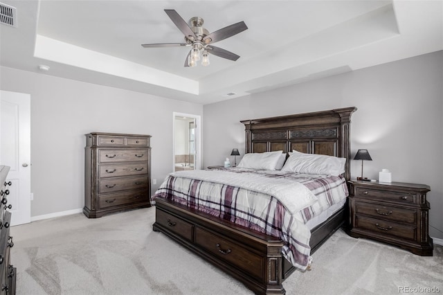 carpeted bedroom with ceiling fan, ensuite bathroom, and a tray ceiling