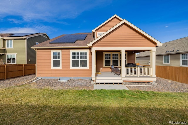 back of house featuring solar panels, a yard, and a deck