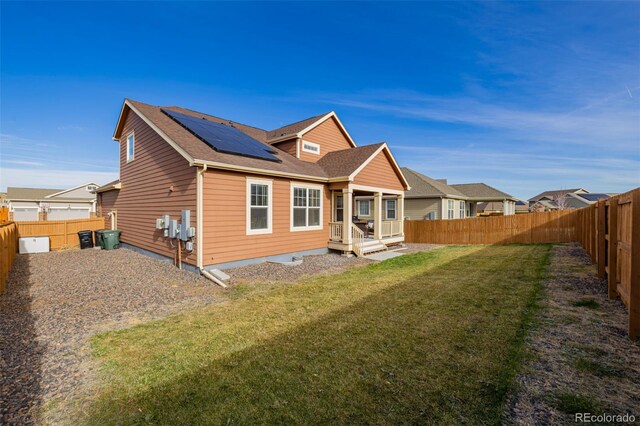 back of property featuring solar panels and a yard