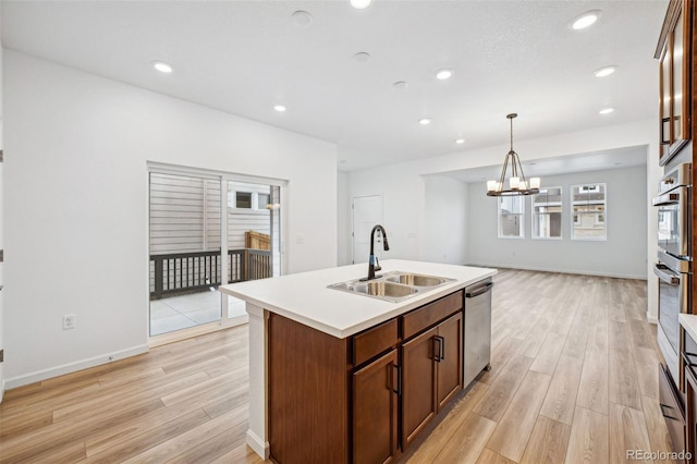 2102 Wagon Wheel Aly, Brighton, CO 80601 - kitchen featuring appliances with stainless steel finishes, light wood-type flooring, a kitchen island with sink, light countertops, and a chandelier