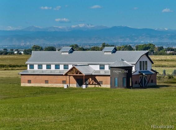 2102 Wagon Wheel Aly, Brighton, CO 80601 - rear view of property featuring a lawn, a mountain view, and a metal roof