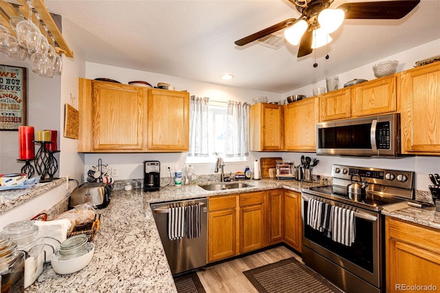 1372 S Cathay Ct Unit 104, Aurora, CO 80017 - kitchen featuring stainless steel appliances, a sink, ceiling fan, light wood-style flooring, and light stone counters