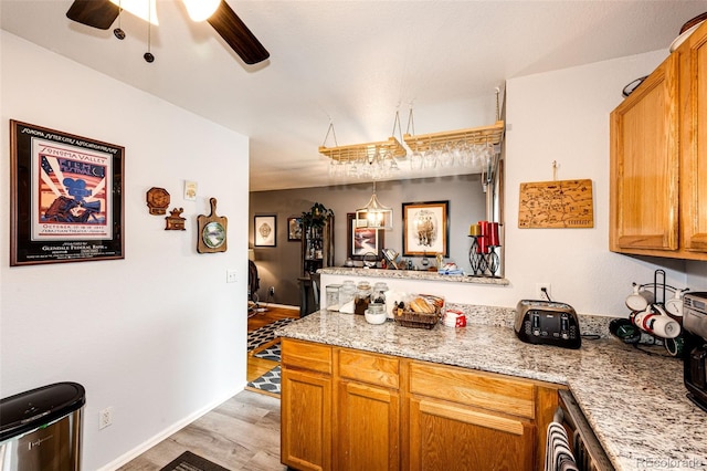 1372 S Cathay Ct Unit 104, Aurora, CO 80017 - kitchen with a peninsula, light wood finished floors, a ceiling fan, brown cabinets, and baseboards