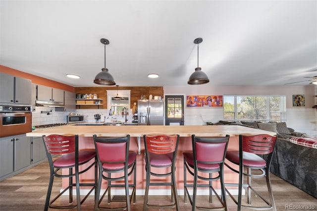 kitchen featuring open shelves, stainless steel appliances, wooden counters, gray cabinetry, and open floor plan