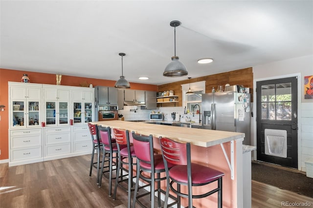 kitchen with appliances with stainless steel finishes, butcher block counters, dark wood finished floors, and open shelves