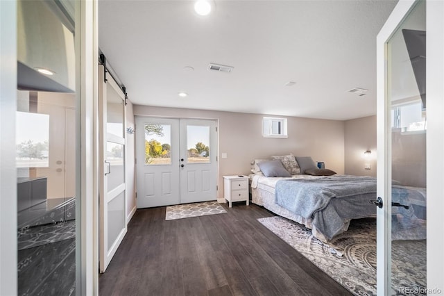 bedroom with dark wood-style floors, french doors, visible vents, and a barn door