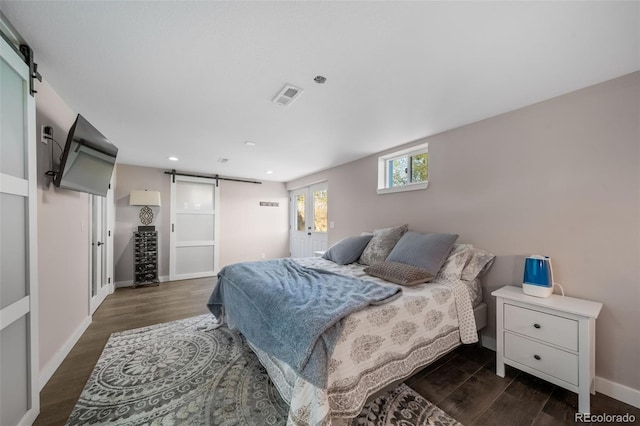 bedroom with baseboards, a barn door, visible vents, and dark wood-style flooring