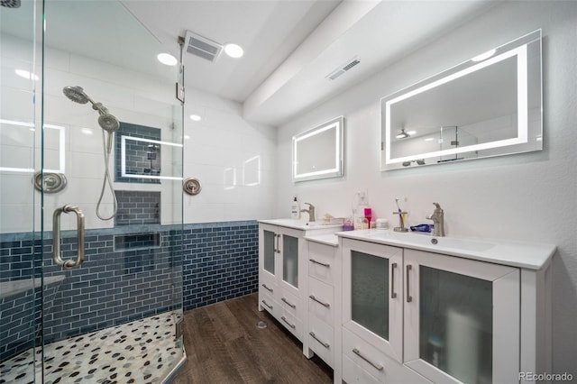 bathroom with a stall shower, visible vents, wood finished floors, and vanity