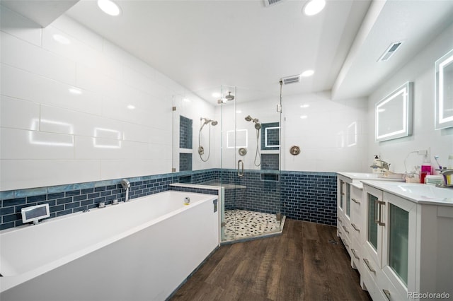 bathroom with tile walls, a freestanding bath, a shower stall, vanity, and wood finished floors