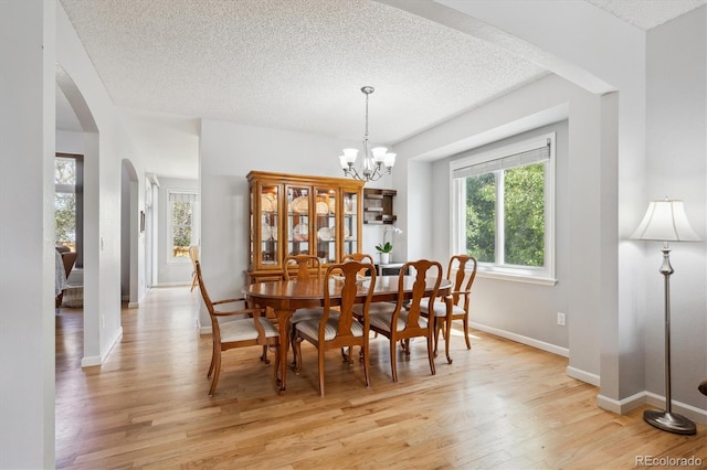 dining area with a textured ceiling, plenty of natural light, and light wood-style flooring