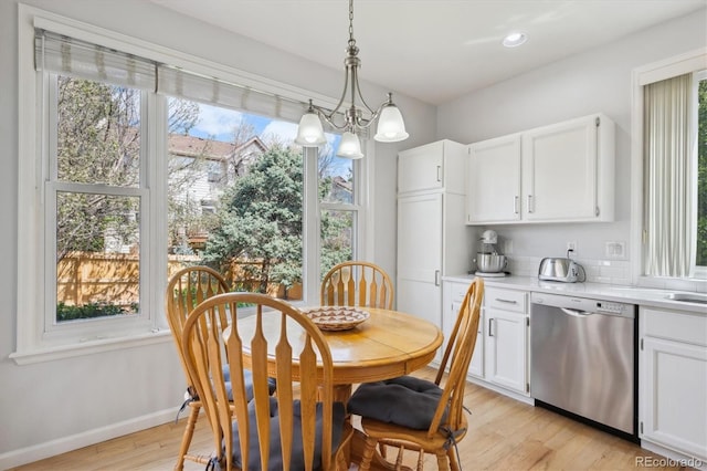 dining room with a chandelier, plenty of natural light, and light wood-style floors