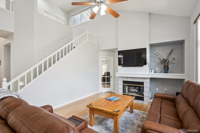 living room featuring stairway, a high ceiling, a ceiling fan, and wood finished floors