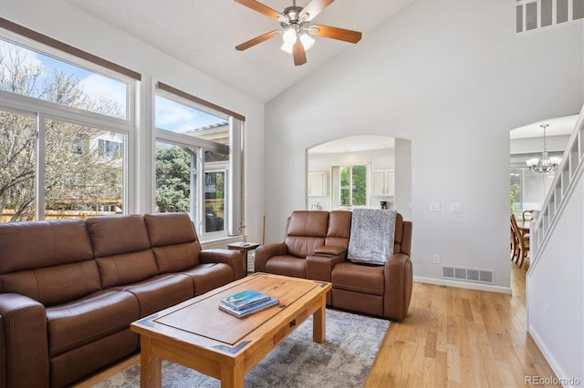 living area with visible vents, plenty of natural light, arched walkways, light wood-style flooring, and ceiling fan with notable chandelier