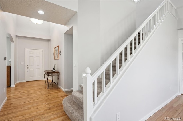 stairs featuring arched walkways, baseboards, recessed lighting, and wood finished floors
