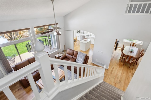 stairs with baseboards, a ceiling fan, wood finished floors, and vaulted ceiling