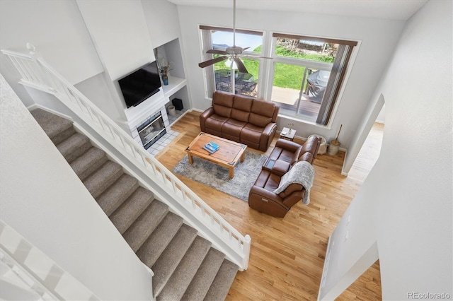 living room featuring a fireplace with flush hearth, arched walkways, wood finished floors, and stairway