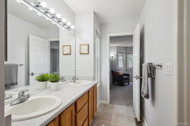bathroom with double vanity, baseboards, a sink, and tile patterned flooring