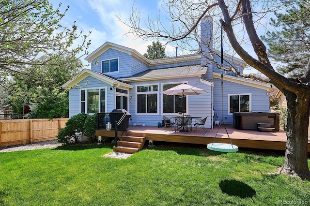 rear view of property featuring a lawn, a hot tub, fence, and a wooden deck