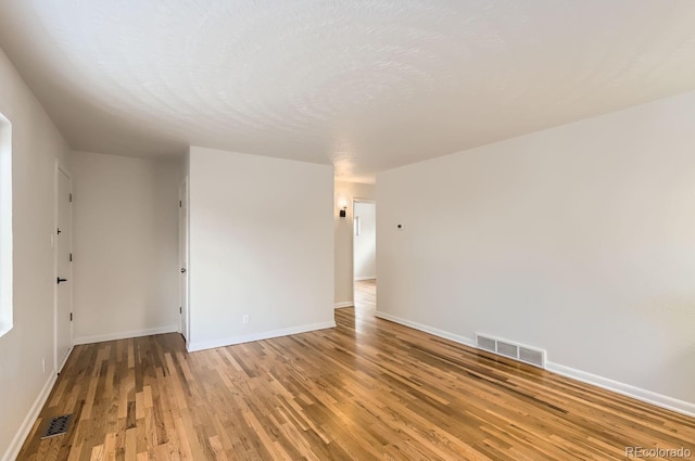 unfurnished room featuring hardwood / wood-style flooring and a textured ceiling