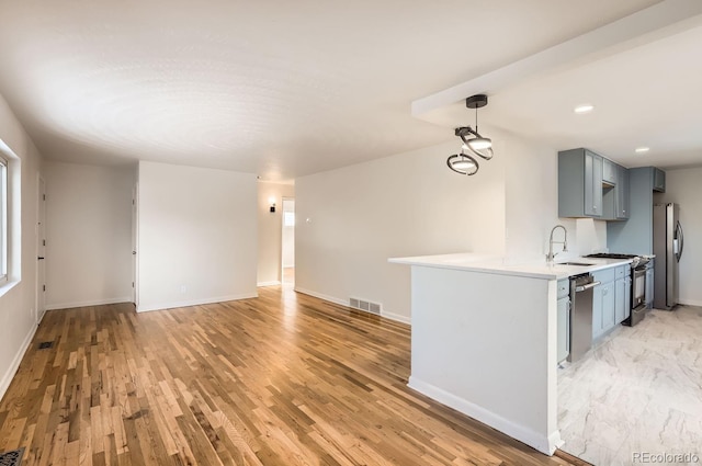 kitchen featuring sink, gray cabinetry, light hardwood / wood-style floors, kitchen peninsula, and stainless steel appliances