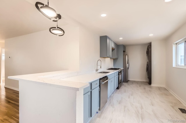 kitchen with sink, gray cabinetry, stainless steel appliances, light stone countertops, and kitchen peninsula